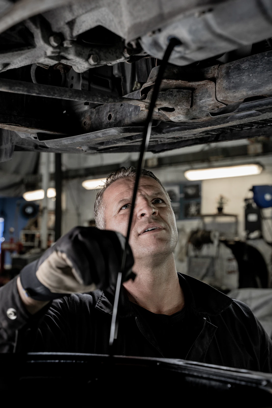 Mechanic working beneath a raised car in an equipped service bay